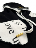 Detail of The Covering Hoodie black drawstring with gold metal aglet against heavyweight black French terry cotton.