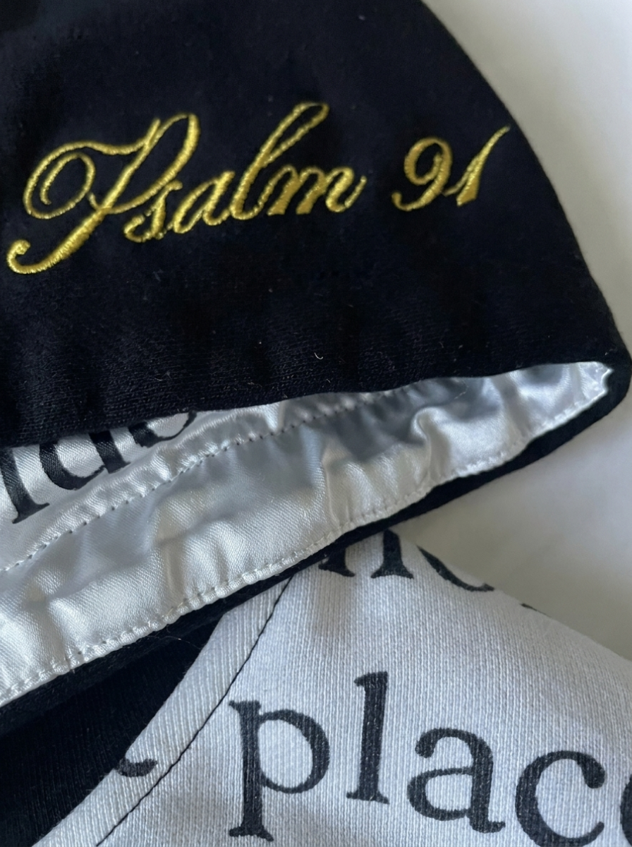 Close-up of gold cursive Psalm 91 embroidery on the black French terry hood of The Covering Hoodie.