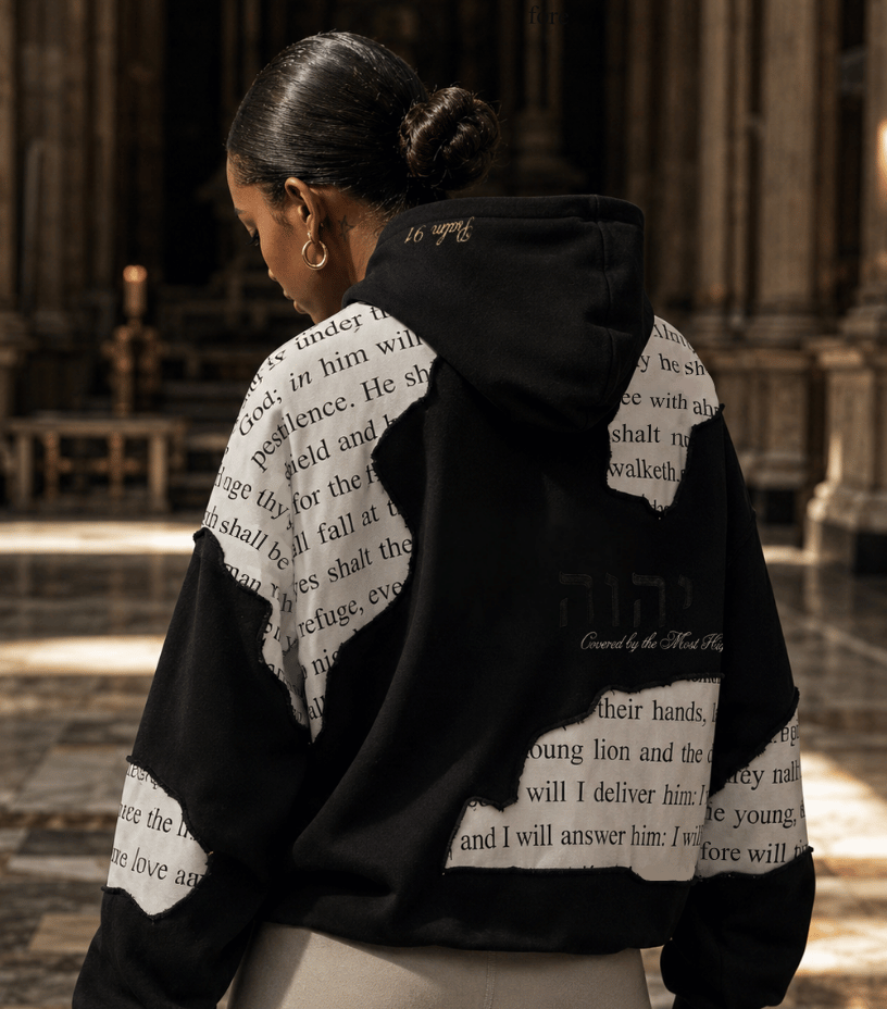 Person wearing a black hoodie with text design in an indoor setting